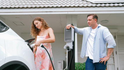 Happy and lovely couple with eco-friendly conscious recharging electric vehicle from EV charging...