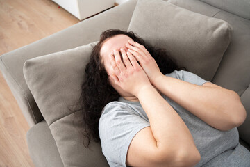 Sad woman complaining in the night lying on a couch in the living room at home