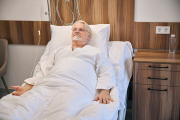 Hospitalized mature male lying in hospital bed - 797076677