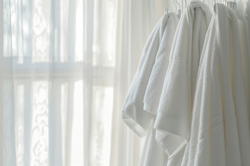 Clean and fresh white towels hanging on a hanger in front of a window in a hotel room