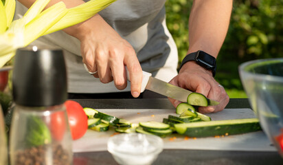 person cuts cucumber for salad