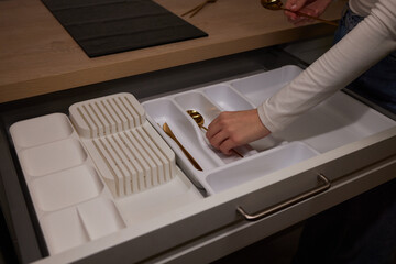 Person grabbing gold fork from black drawer with handles