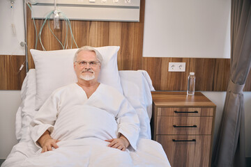 Hospitalized mature man lying in hospital bed - 797081247