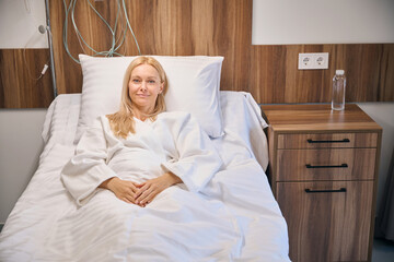 Hospitalized smiling female lying in hospital bed - 797081416