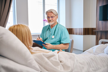Male specialist holding tablet and talking to female patient