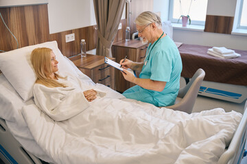 Male specialist holding tablet and talking to lady patient - 797083663