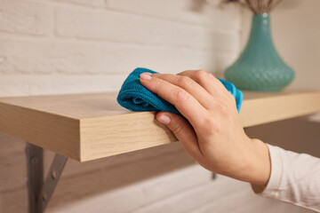 Cleaning a shelf using a blue cloth made of wood stain