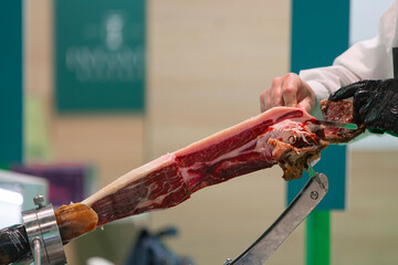 A man is cutting a piece of ham with a knife