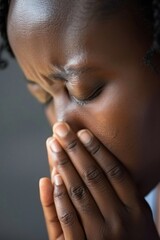 She is making a worried gesture, covering her mouth with her hands
