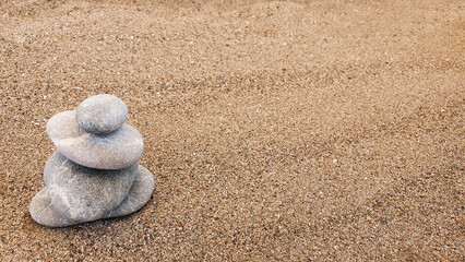 Spa stones balance on the sand of the beach.