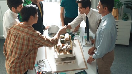 Top view of manager shake hands and making a deal at meeting table with architectural model,...