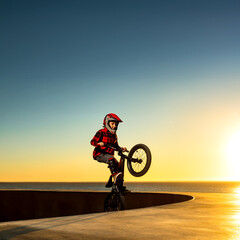 Naklejka premium A teenager BMX Racing Rider performs tricks in a skate park on a pump track.