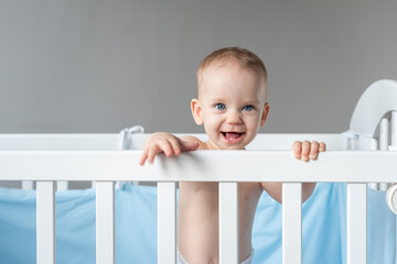 Laughing baby reaching out from his crib