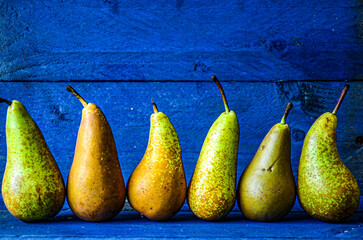 Original natural pears stand in a row on a blue background.