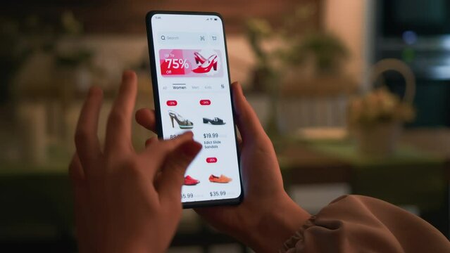 Shopping online for shoes using smartphone retail app. Sale with great discounts and special offers. Scrolling through a catalog of shoes. Fictional interface.