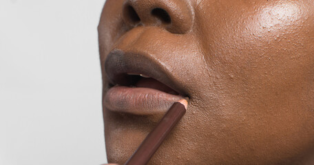Brown skin woman applying a brown lip liner, dark skinned woman using lip product, makeup...