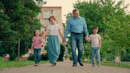 Family walk in park holding hands. Mom, dad, child, big family. Happy family with children walks...