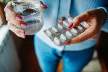 A close up of woman's hand holding pills and glass of water	
