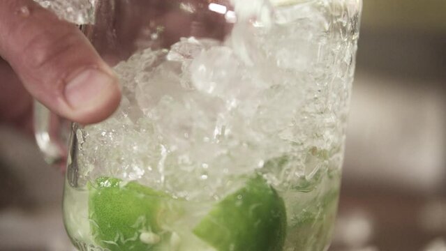 Crushed ice added to cocktail glass with lime