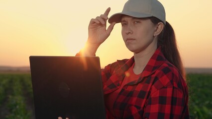 Portrait farmer with laptop at sunset. Close-up female farmer use laptop work field. Woman agronomist work computer during field work season. Concept usage modern digital technologies in agribusiness