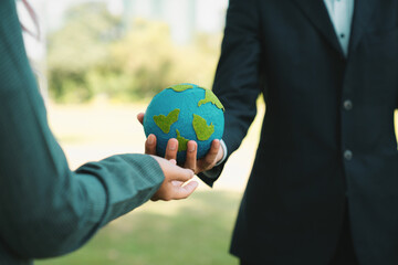 Earth day concept, businessman giving Earth globe to colleague as CSR corporate social responsible...