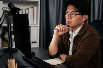 Smart businessman in casual day focusing computer to create business plan report over late night...