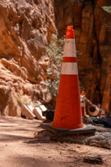 Orange caution cone on Zion red sandstone cliffs park trail construction. Cement mixer. Selective...