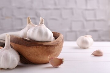 Fresh garlic on white wooden table, closeup. Space for text