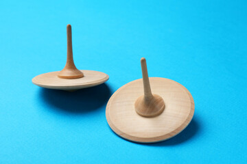 Two wooden spinning tops on light blue background