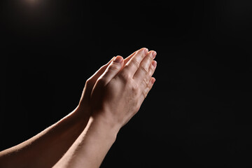 Religion. Christian woman praying on black background, closeup. Space for text