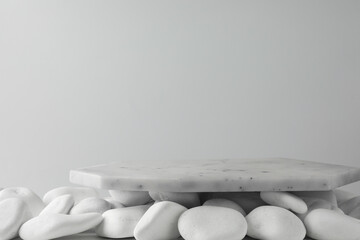 Presentation for product. Marble podium and white pebbles on light background. Space for text