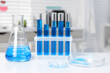 Laboratory analysis. Different glassware with blue liquid on white table indoors