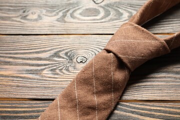 One striped necktie on wooden table, above view. Space for text