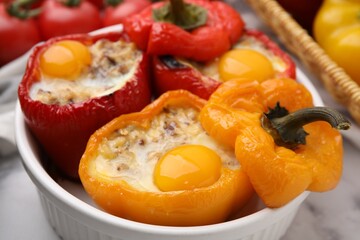 Delicious stuffed peppers with eggs in bowl on white table, closeup