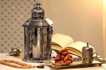 Arabic lantern, Quran, misbaha and dates on white table