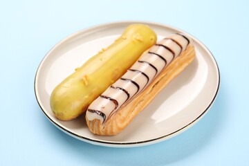 Delicious eclairs covered with glaze on light blue background