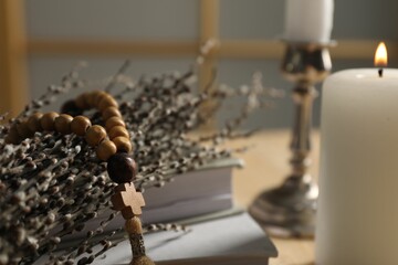 Rosary beads and willow branches on table, closeup. Space for text