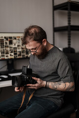A male photographer in casual wear examines a vintage camera indoors, showcasing his passion for photography and expertise.