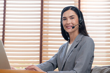Female call center operator or customer service helpdesk staff working on workspace while talking...