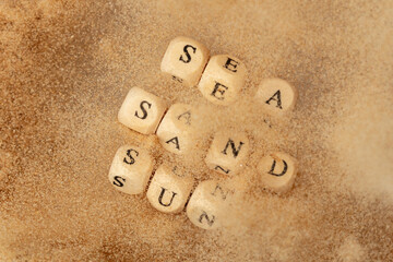 Alphabet letter wording "Sea Sand Sun" bead toy flying over explosion flying in air. Sea Sand Sun word alphabet letter show tropical island beach sand for vacation holiday. Top view action