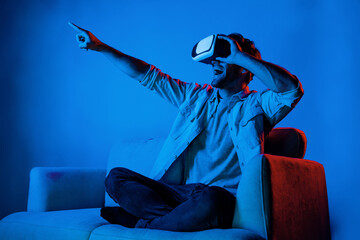 Man pointing and choosing program in simulated metaverse by using VR glasses. Person with headset...