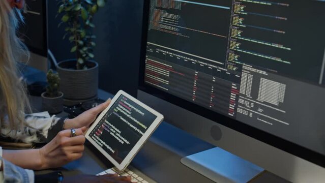Medium close-up of hands of multiethnic software developers working together on mobile application project in IT startup office, studying code on computer screen and tablet, discussing problem