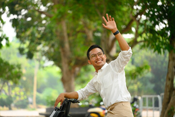 Cheerful male worker riding bicycle and waving hand as greeting someone. People and transport...