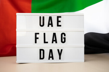 Lightbox with text UAE FLAG DAY on United Arab Emirates waving flag made from silk material....