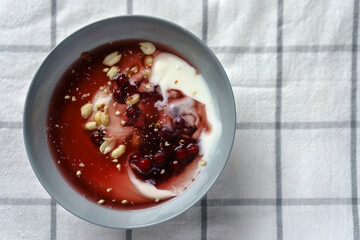 Bowl filled with yogurt, topped with fresh red berries and crunchy peanuts