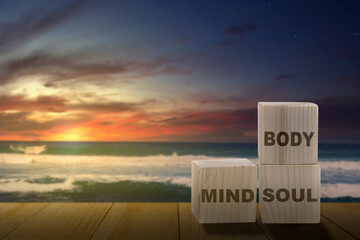 Stack of small wooden cubes with the text of mind, body, and soul on the table