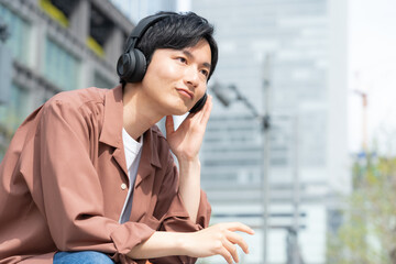 オフィス街で音楽を聴く若い男性