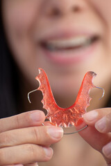 Closeup of hawley retainer held by happy person in blurred background, concept of oral health,...
