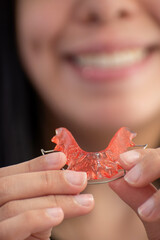 Closeup of hawley retainer held by person in background out of focus, concept of oral health, orthodontics, orthopedics. selective focus.