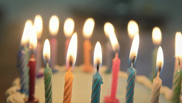 gently flickering birthday candles in a row on cake